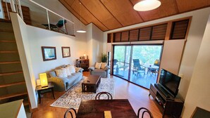A spacious living room with a wooden dining table, a sofa, and a TV. - Sapphire Villa 535, Kingfisher Bay Resort, K'gari (Fraser Island)
