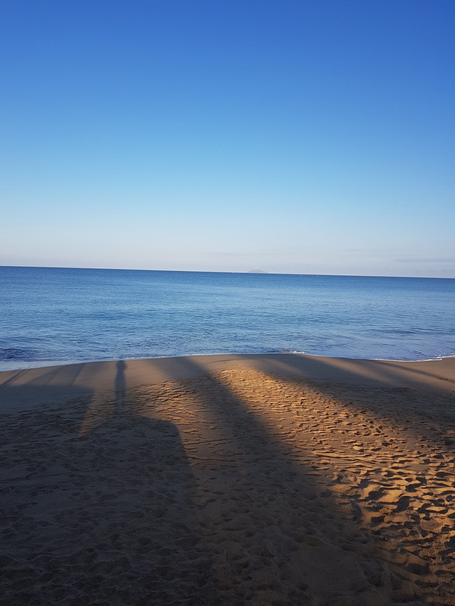 Une plage avec un ciel dégagé et une mer calme.
