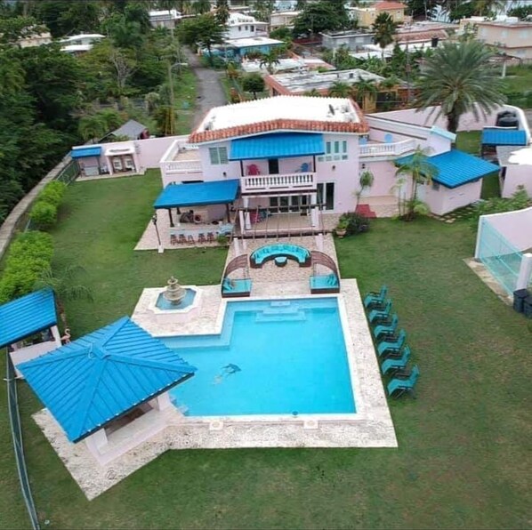 Una casa grande con piscina y un patio cubierto.