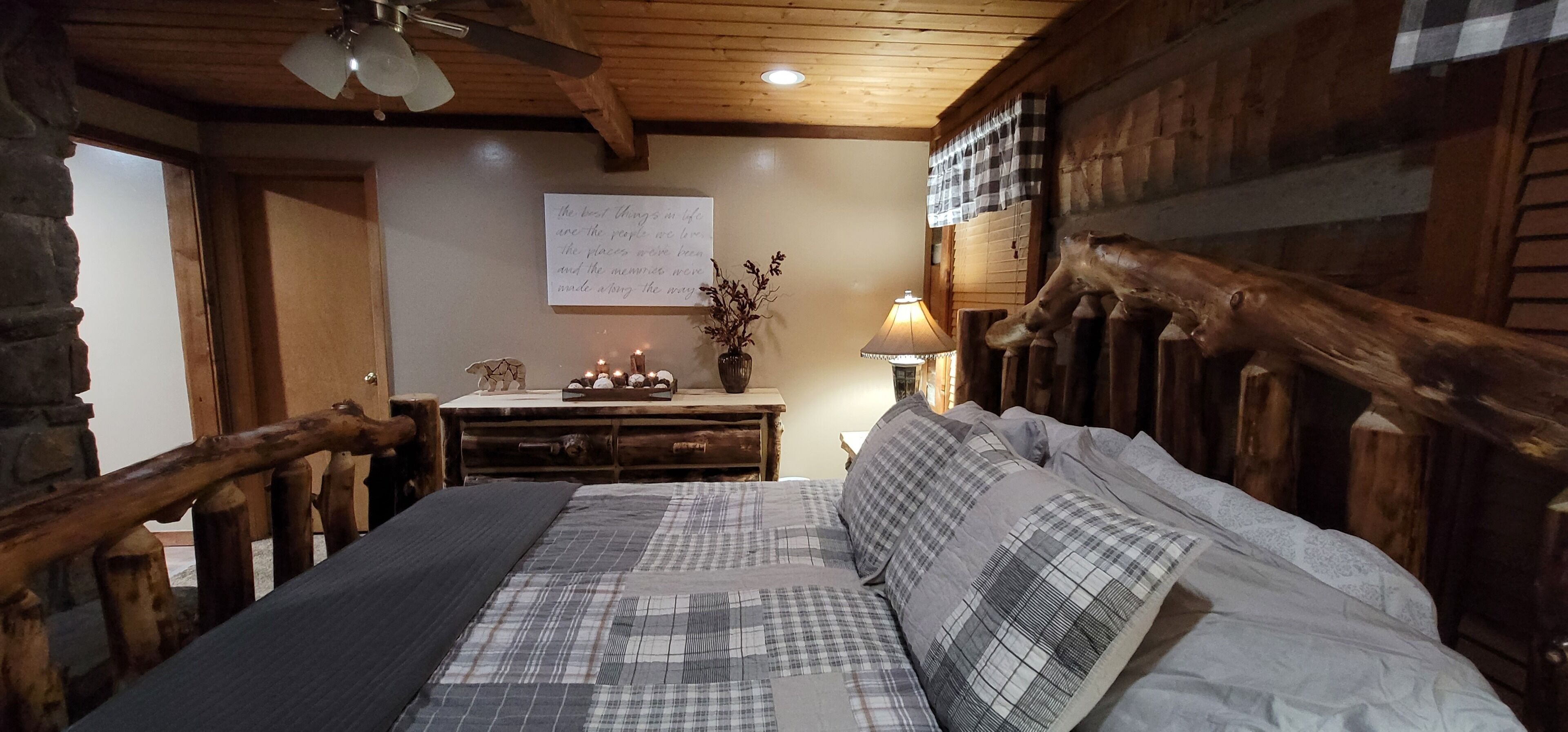 Ein gemütliches Zimmer mit einem hölzernen Bett, einem Nachttisch mit Kerzen und einer Wand mit einer handgeschriebenen Notiz.