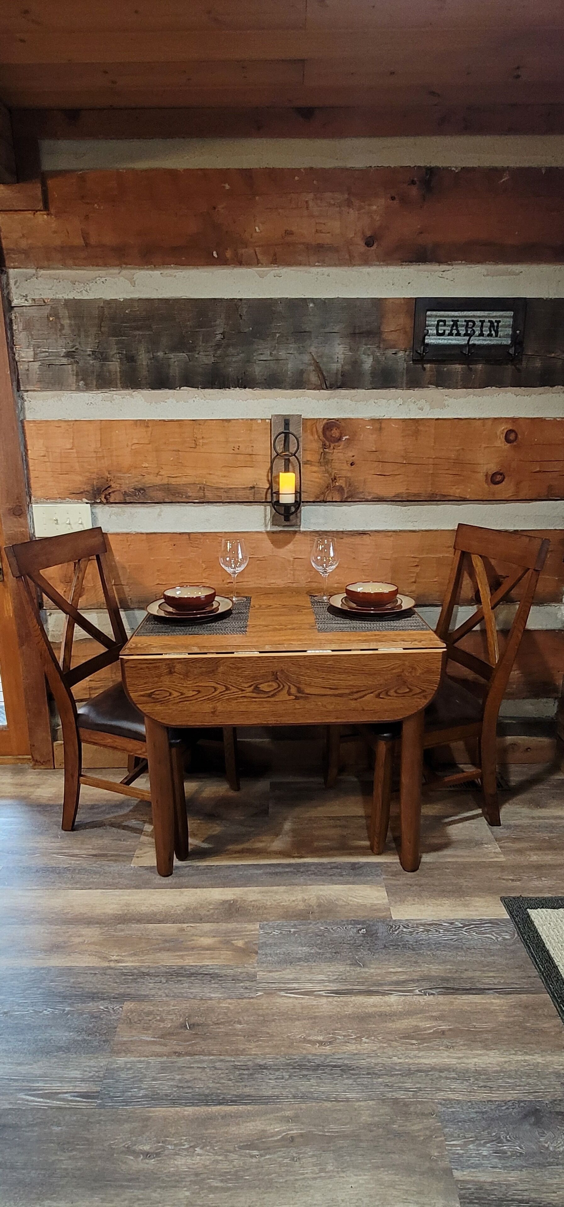 Ein Holztisch mit zwei Stühlen, einer Kerze und zwei Weingläsern.
