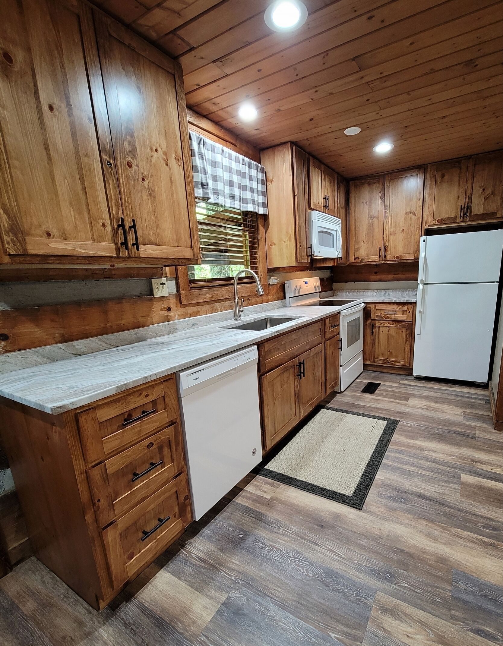 A kitchen with wooden cabinets, a white refrigerator, a microwave, and a dishwasher.
