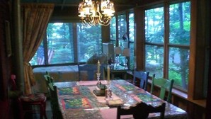 Comedor con una mesa cubierta por una camino de mesa, rodeada de sillas y un candelabro.