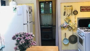 Una cocina con un refrigerador blanco, una mesa de madera y un jarrón con flores, además de una estufa.