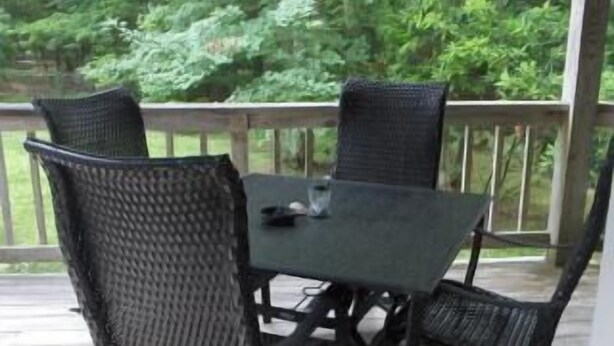 Une terrasse extérieure couverte, avec une table et quatre chaises.