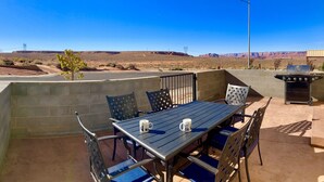 An outdoor patio with a table and chairs, a barbecue grill, and a view of a desert landscape. - 🏜️Local VIEW~🐶Pet Friendly-🚤BOAT Parking~Close to AntelopeCanyon~HorseshoeBnd (Page)