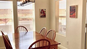 A dining area with a wooden table and chairs, a pendant light, and two windows with blinds. - 🏜️Local VIEW~🐶Pet Friendly-🚤BOAT Parking~Close to AntelopeCanyon~HorseshoeBnd (Page)