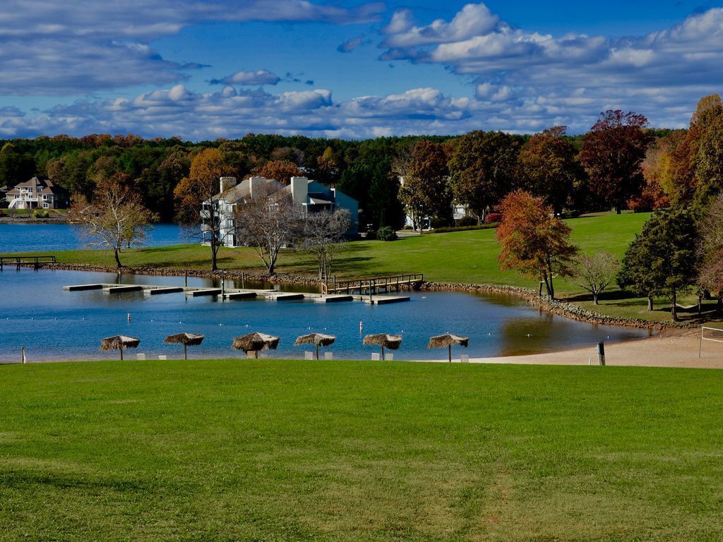 A lakeside property with a dock, a grassy area, and a large house.