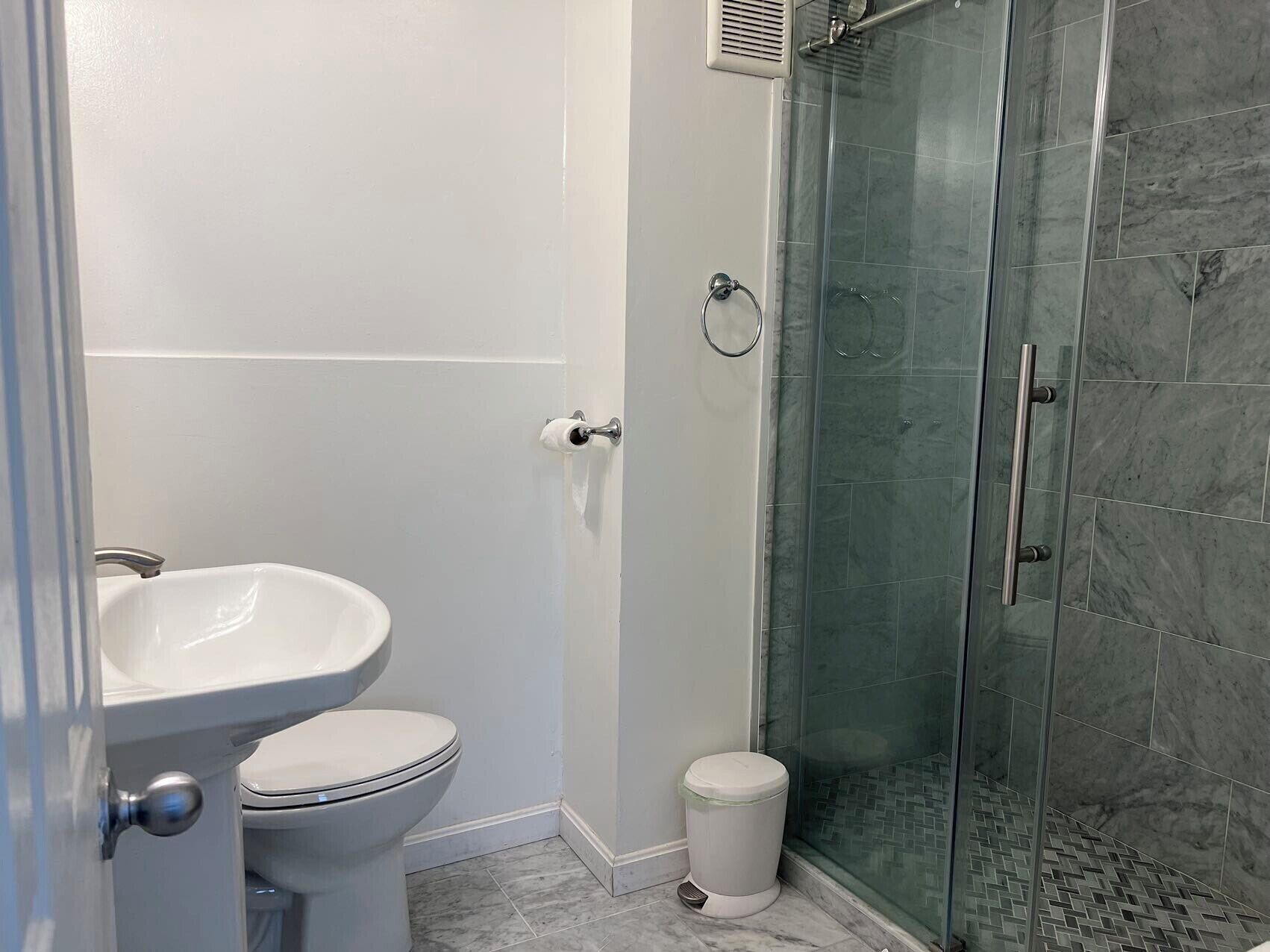 Een badkamer met toilet, wastafel en douchecabine.