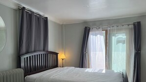 Une chambre à coucher avec un lit, une lampe de chevet, un radiateur et des rideaux.
