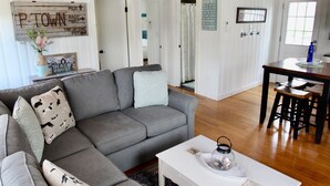 Un soggiorno moderno con un divano angolare grigio, un tavolino da caffè bianco e travi in legno al soffitto.