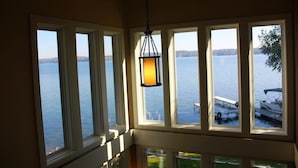 Una stanza con ampie finestre vista lago, un lampadario appeso e una barca ormeggiata all'esterno.