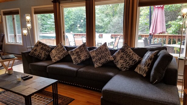 Una sala de estar acogedora con un sofá modular, una mesa de centro y vistas al exterior a través de amplias ventanas.