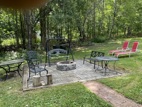 An outdoor patio with a fire pit, metal chairs, and a table. - Experience The Catskill Getaway. Not your typical vacation rental (West Kill)