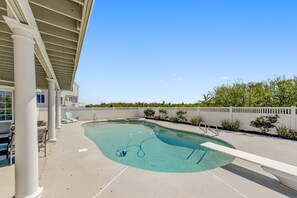 A swimming pool with a diving board, lounge chairs, and a covered patio area. - Luxury Ocean Front Mansion with Heated Pool, Elevator, Grill and Suites Galore (Brigantine)