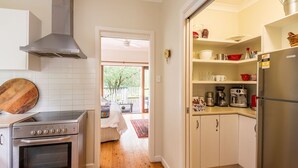 Une cuisine compacte avec des meubles blancs, une cuisinière en acier inoxydable et un four encastré.