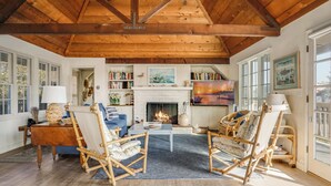 A cozy living room with a fireplace, wooden beams, and comfortable seating. - Gated Fairytale Estate | Lakefront w/ Ocean Views (Oceanside)