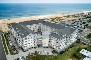 Un hôtel à plusieurs étages doté d’une cour intérieure, situé près d’une plage où l’on peut voir le sable et l’océan.