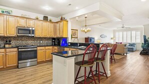 A spacious kitchen with wooden cabinets, a built-in microwave, and a large island with red chairs. - Seaside Delight | 350 ft from the beach | Community Pool (Virginia Beach)