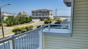 A residential property with a balcony, a driveway, and a large house in the background. - Seaside Delight | 350 ft from the beach | Community Pool (Virginia Beach)