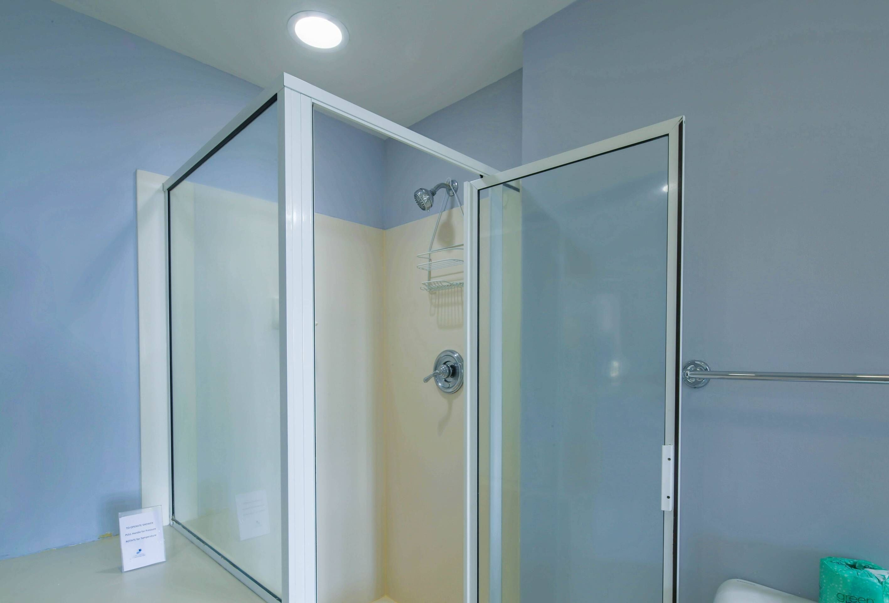 A glass-enclosed shower with a chrome showerhead and a towel rack.
