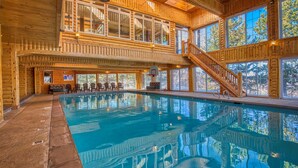 Une cabane en bois dotée d’une piscine, de plusieurs terrasses et de grandes fenêtres.
