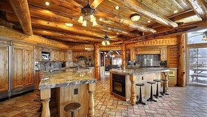 Une cuisine spacieuse dotée de meubles en bois, de plans de travail en granit et d’un îlot central avec des tabourets.