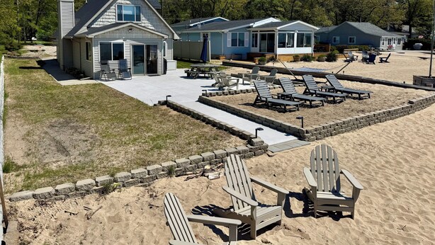 A beachfront property with a covered patio, lounge chairs, and a swimming pool.