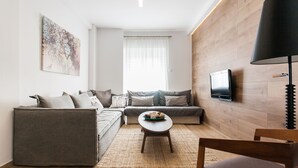 Una sala de estar moderna con un sofá, una mesa de centro y un televisor en la pared.