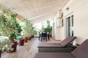 A covered patio with wicker lounge chairs, potted plants, and a dining table. - Walking distance to all attractions, safe, superb (Athina)