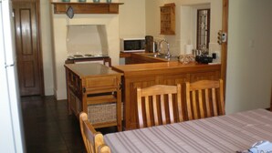Une cuisine compacte équipée d’un four à micro-ondes, d’un évier et de meubles en bois. Un petit coin repas avec une table et des chaises est également disponible.