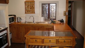 Une cuisine dotée de meubles en bois, d’un plan de travail en granit, d’un évier et d’une fenêtre agrémentée d’une porte en verre décorative.
