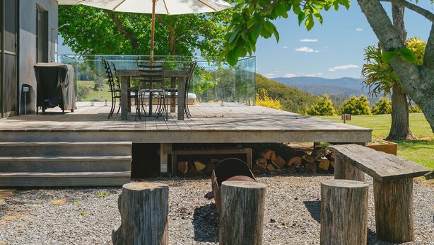 Une terrasse extérieure avec une table et des chaises, un parasol et une vue sur le paysage.