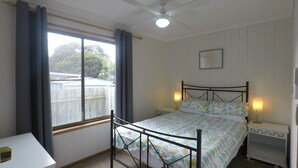 A bedroom with a bed, bedside tables, a ceiling fan, and a window with curtains. - CHA CHA - Pet Friendly-Netflix WiFi  (Inverloch)