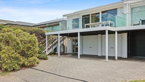 Et moderne hus med to etager, en glasbalkon, en overdækket indkørsel og en garage.