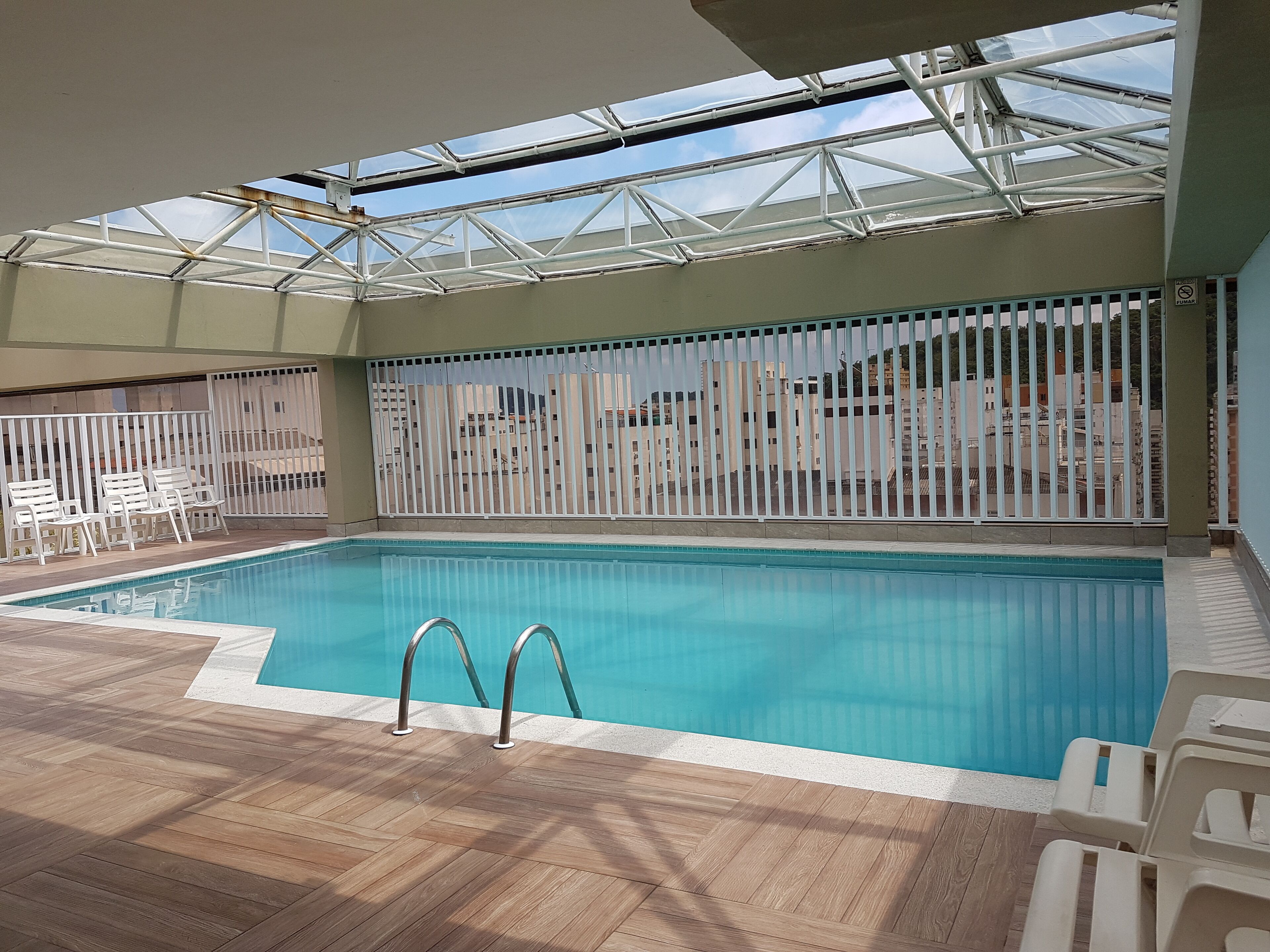 Deliciosa piscina aquecida com teto de vidro na cobertura do prédio. 