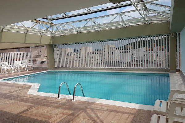 Deliciosa piscina aquecida com teto de vidro na cobertura do prédio.