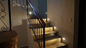 Un escalier avec une rampe en bois et un luminaire sur chaque marche.