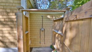 A wooden gate leading to a covered outdoor area with a brick wall and a metal pipe. - Quintessential MV home near Oak Bluffs, beach & harbor (Oak Bluffs)