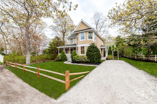 A two-story house with a front porch, a driveway, and a well-maintained lawn.