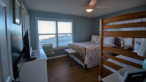 Una camera da letto con un letto a castello, una scrivania con un computer, una sedia e una finestra con persiane.