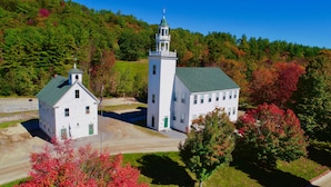 A white church with a bell tower and a separate building with a green door, surrounded by autumn foliage. - Private Beach And  Mountain Lake Home (Washington)