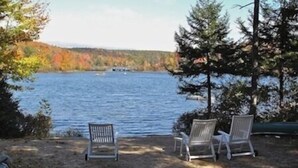 Two white chairs facing a lake with autumn foliage in the background. - Private Beach And  Mountain Lake Home (Washington)