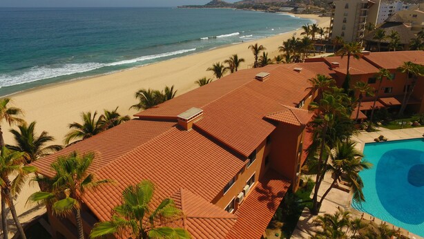 A resort with a beach view, a swimming pool, and palm trees. - Beachfront Condo on Costa Azul Beach in Los Cabos Mexico (San Jose del Cabo)