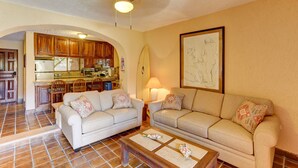 Ein Wohnzimmer mit zwei Sofas, einem Couchtisch und einer Küche im Hintergrund.