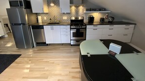 Une cuisine compacte dotée d’appareils électroménagers modernes, un coin repas et un petit espace de travail.