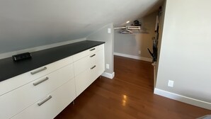 Une pièce moderne et bien éclairée, dotée d’un plancher en bois, d’une commode blanche avec des tiroirs, d’un comptoir noir et d’un porte-manteau suspendu.