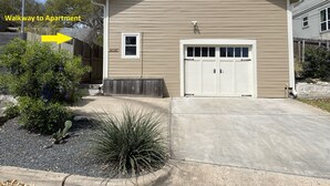 Une maison à deux étages, à la façade de couleur beige, avec un garage et un chemin menant à un appartement.