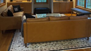 Ein geräumiges Wohnzimmer mit Deckenventilator, einem großen Bogenfenster, einem Flachbildfernseher und einer gemütlichen Sitzecke mit gemustertem Teppich.