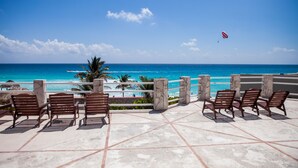 A terrace with wooden chairs and a view of the ocean. - A WINDOW TO PARADISE (Cancún)